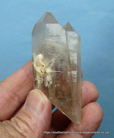 Twin quartz crystals with bits of feldspar attached